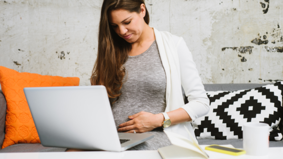schwangere Frau mit Laptop im Schoß 